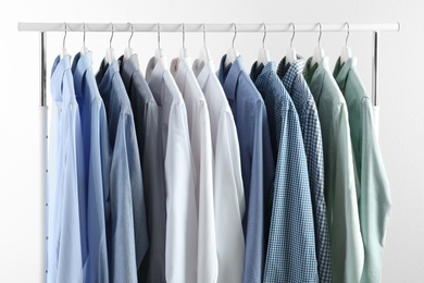 Photo of Men's clothes hanging on wardrobe rack against white background