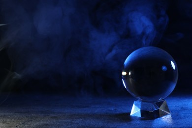 Photo of Magic crystal ball on table against dark background, space for text. Making predictions