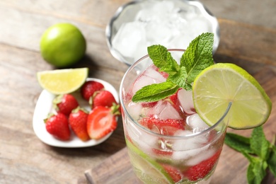 Photo of Glass of natural lemonade with lime, strawberries and mint on table, closeup