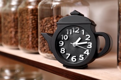 Photo of Teapot shaped clock on shelf with jars of coffee beans