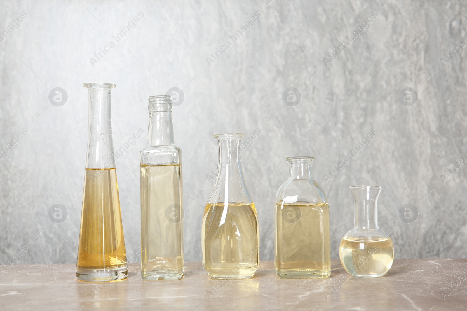 Photo of Row of different glass bottles with oil on color background