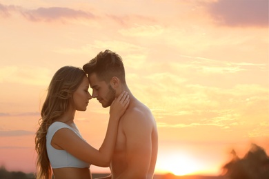 Happy young couple in beachwear outdoors at sunset