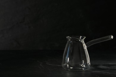 Empty glass turkish coffee pot on black table. Space for text