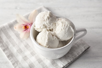 Photo of Cup with tasty vanilla ice cream on wooden background