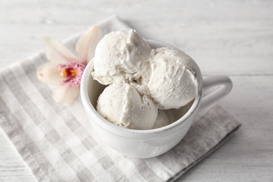 Cup with tasty vanilla ice cream on wooden background