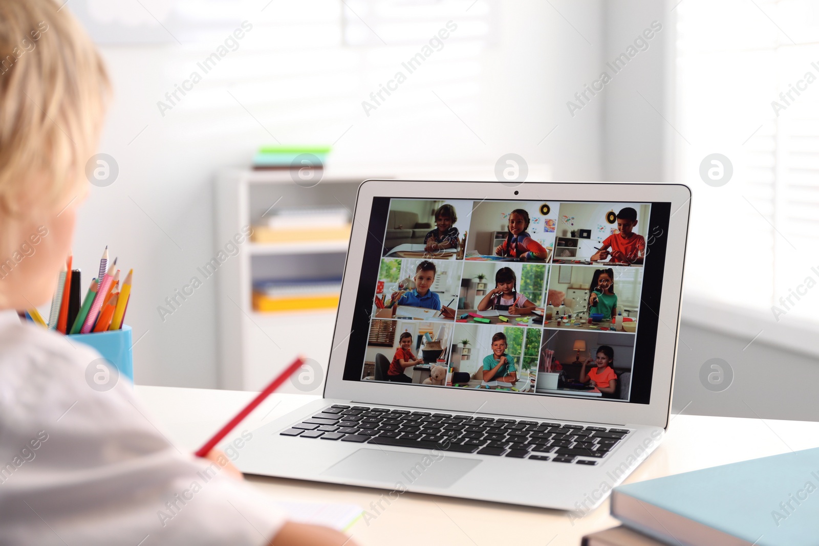 Photo of Little boy studying with classmates via video conference at home. Distance learning during COVID-19 pandemic