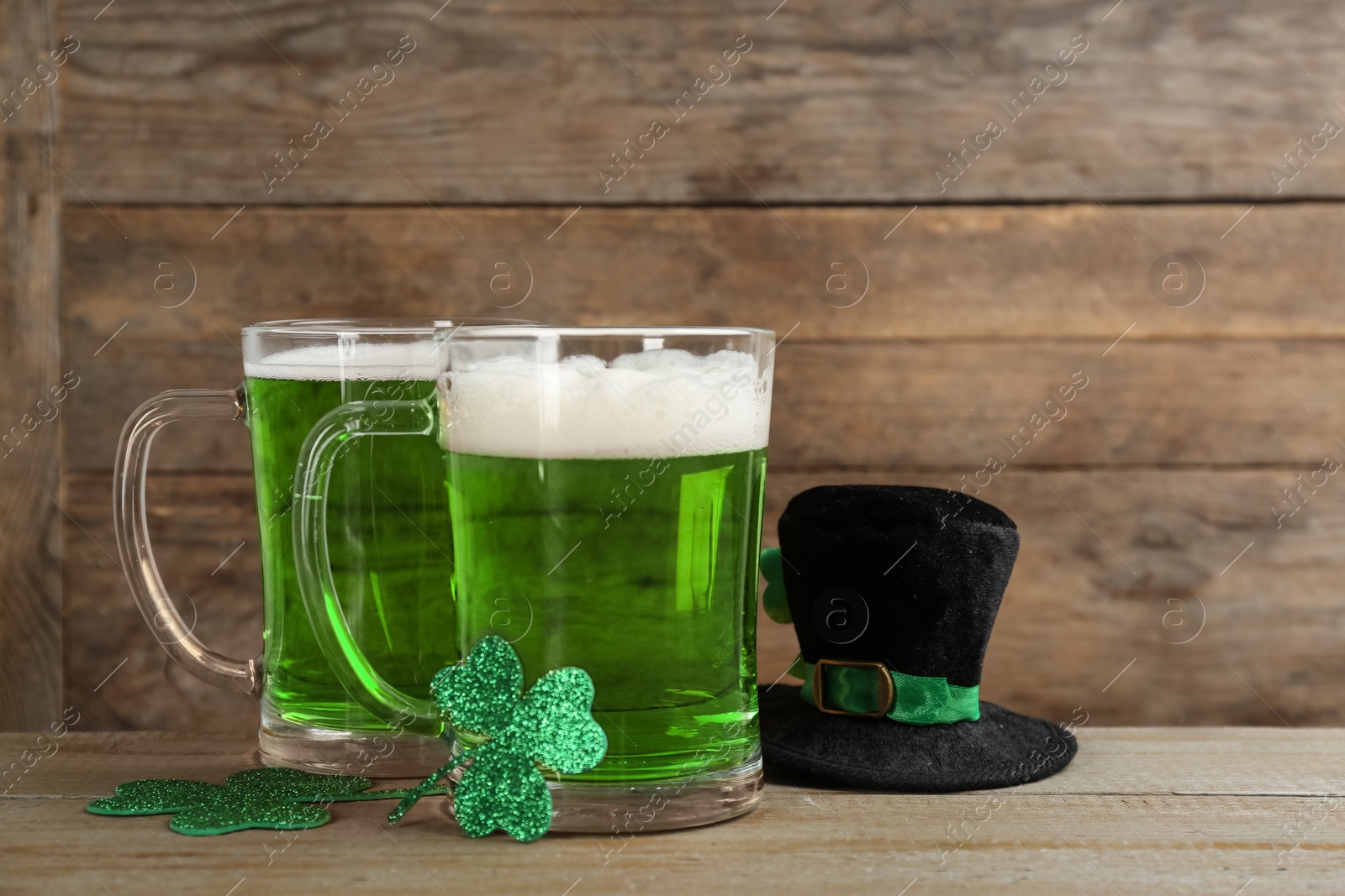 Photo of Green beer, hat and clover leaves on wooden table. St. Patrick's Day celebration