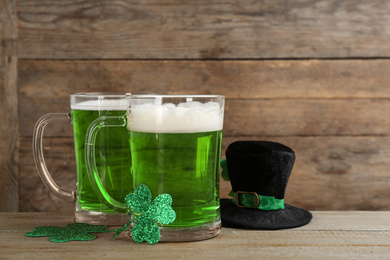 Photo of Green beer, hat and clover leaves on wooden table. St. Patrick's Day celebration