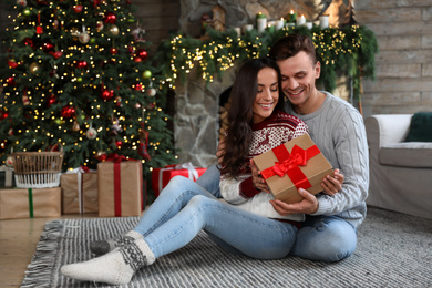 Happy couple with gift box in living room decorated for Christmas