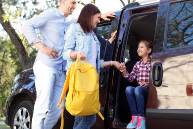 Photo of Young parents taking their little child to school by car