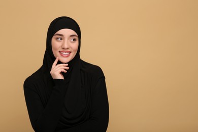 Portrait of Muslim woman in hijab on beige background, space for text