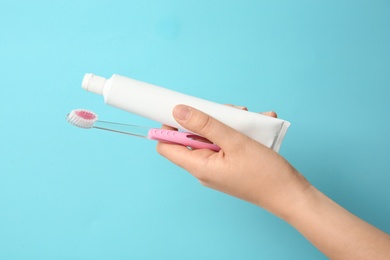 Woman holding toothbrush and paste against color background. Dental care