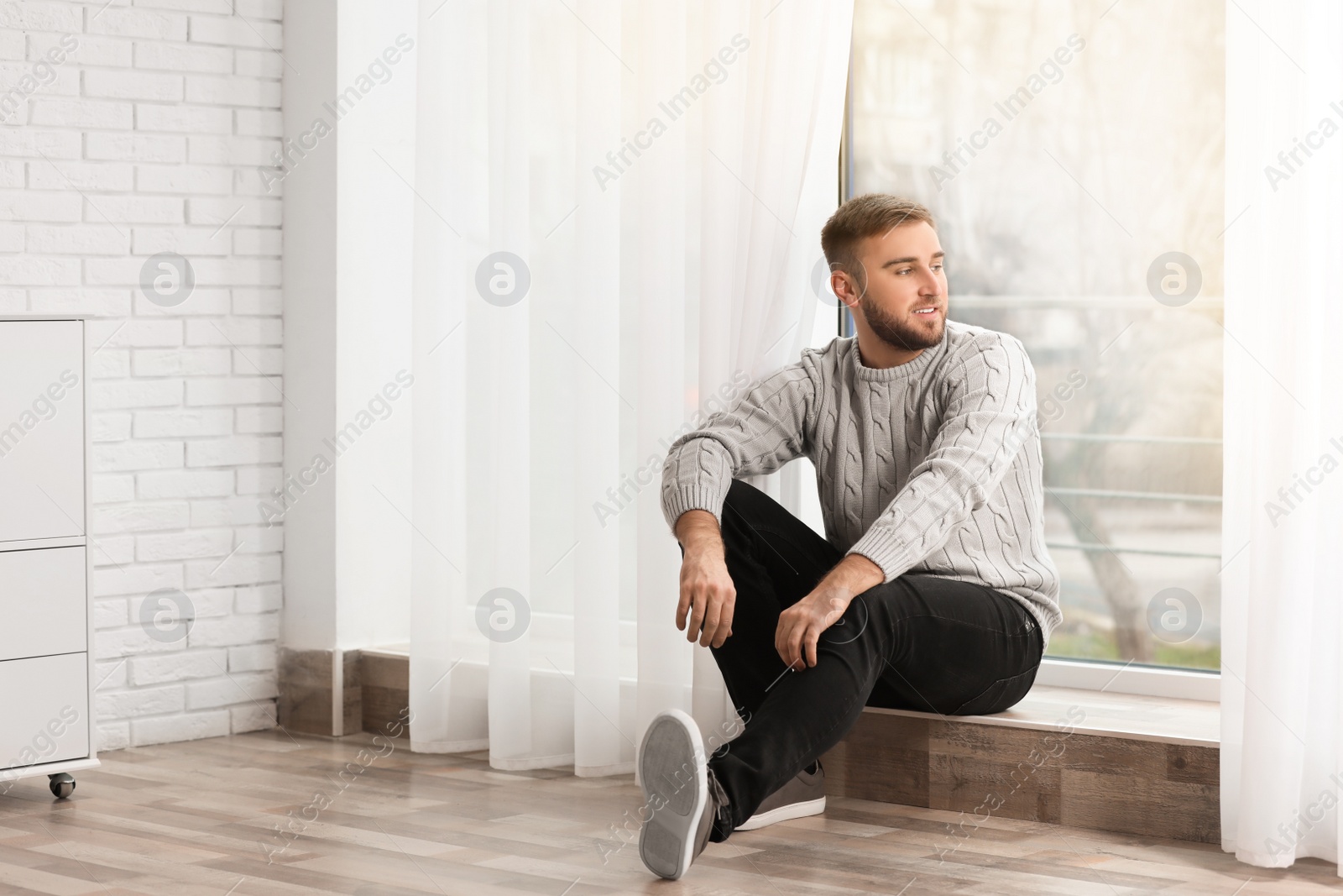 Photo of Handsome young man near window at home