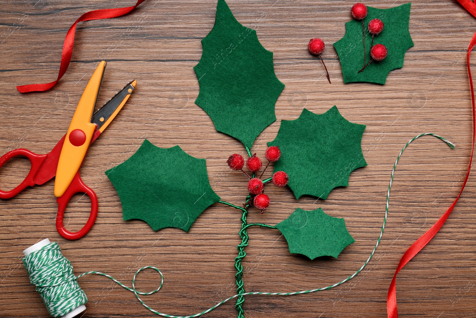 Photo of Set of instruments and materials for making mistletoe branch on wooden table, flat lay