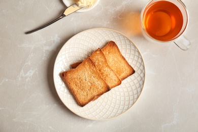 Photo of Plate with toasted bread and cup of tea on light background, top view