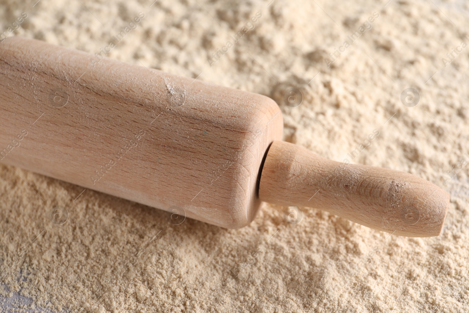 Photo of Rolling pin and scattered flour on table, closeup