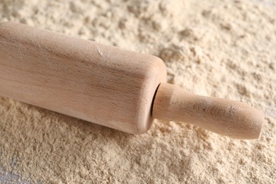 Photo of Rolling pin and scattered flour on table, closeup