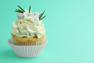 Tasty Easter cupcake with vanilla cream on turquoise background, space for text