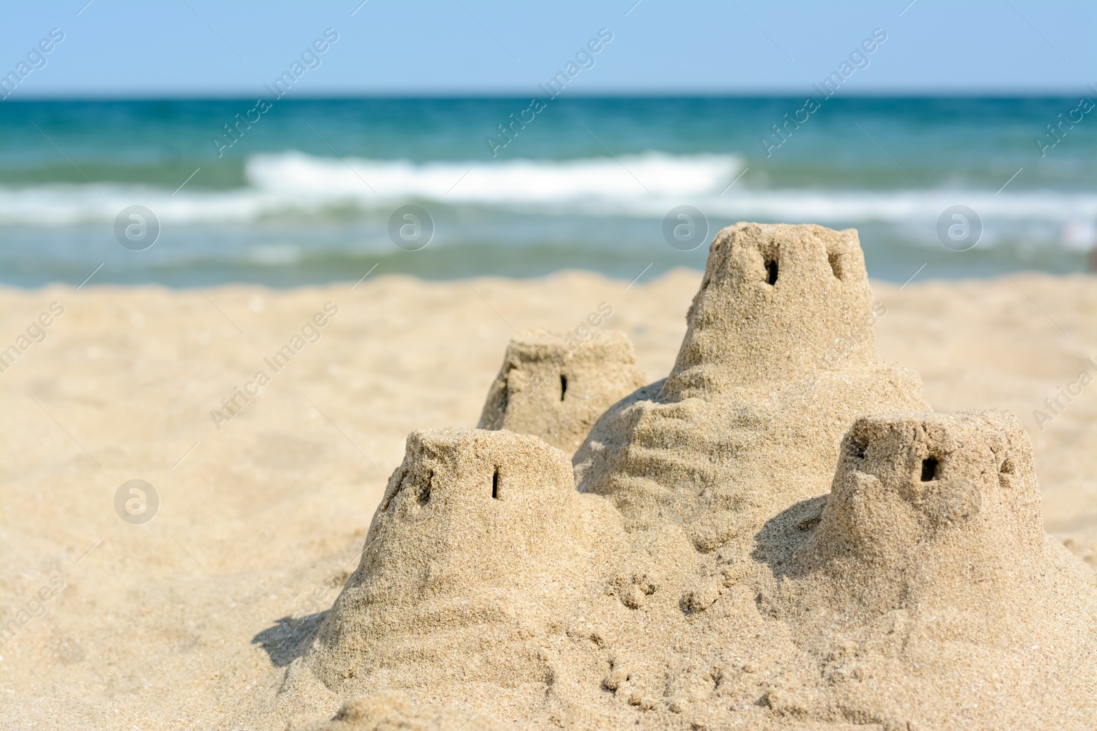 Photo of Beach with sand castle near sea on sunny day. Space for text