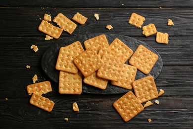 Photo of Delicious crispy crackers on black wooden table, flat lay