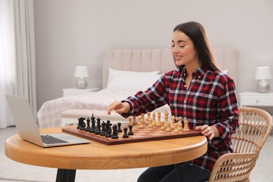 Photo of Young woman playing chess with partner through online video chat at home