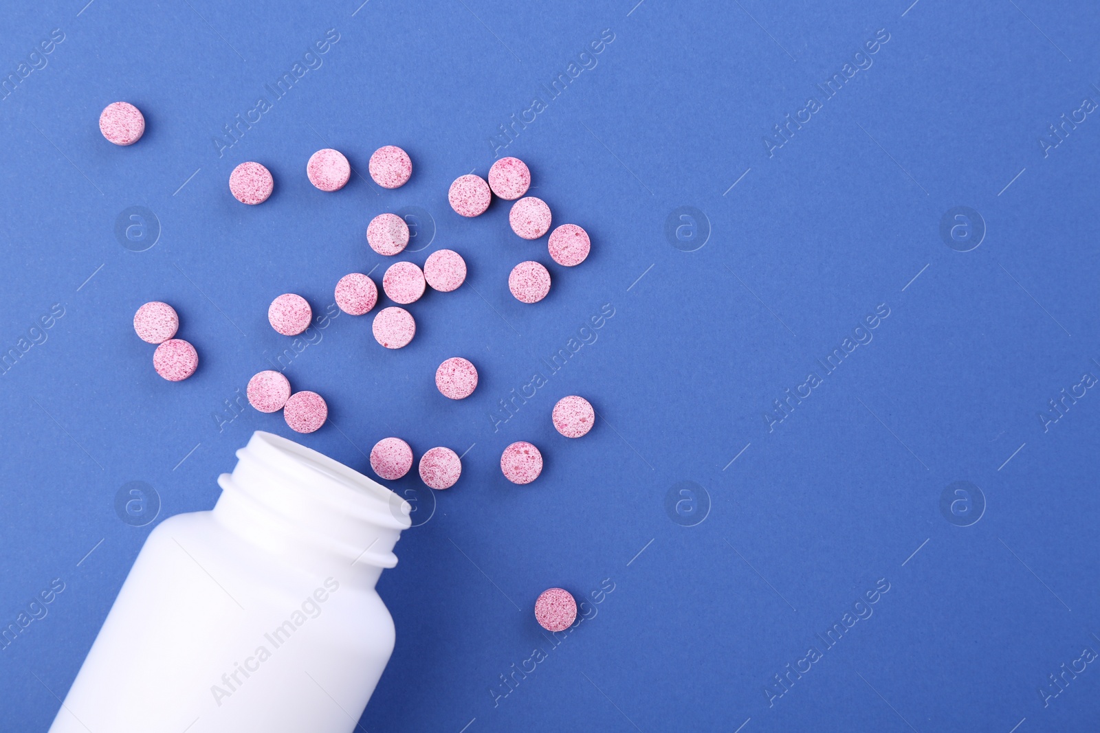 Photo of Bottle and vitamin pills on blue background, top view. Space for text