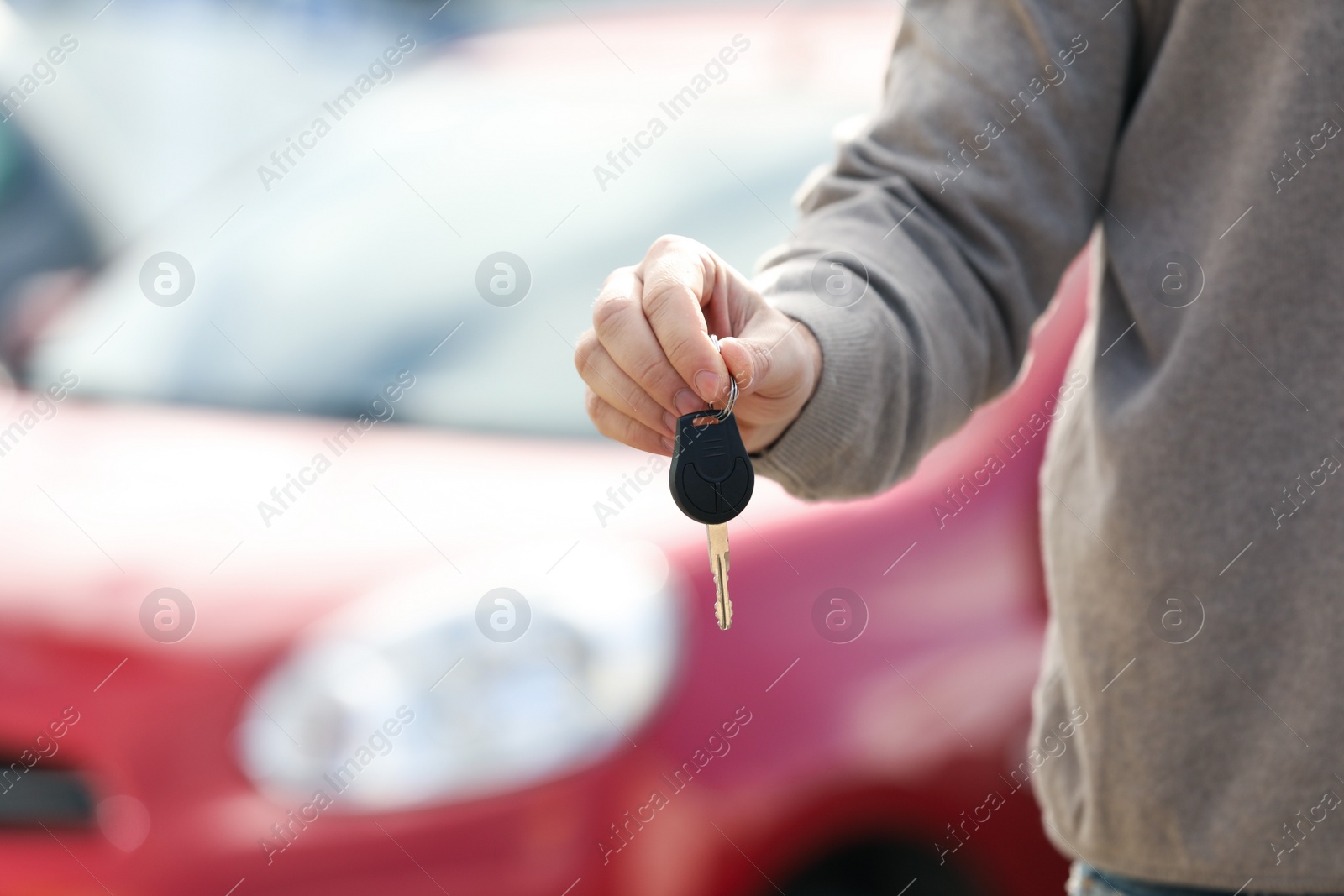 Photo of Man holding key in modern auto dealership, closeup. Buying new car