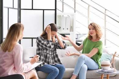 Young woman and her teenage daughter visiting child psychologist in office