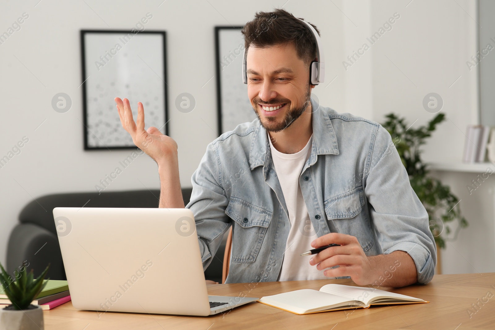 Photo of Man in headphones studying on laptop at home. Online translation course