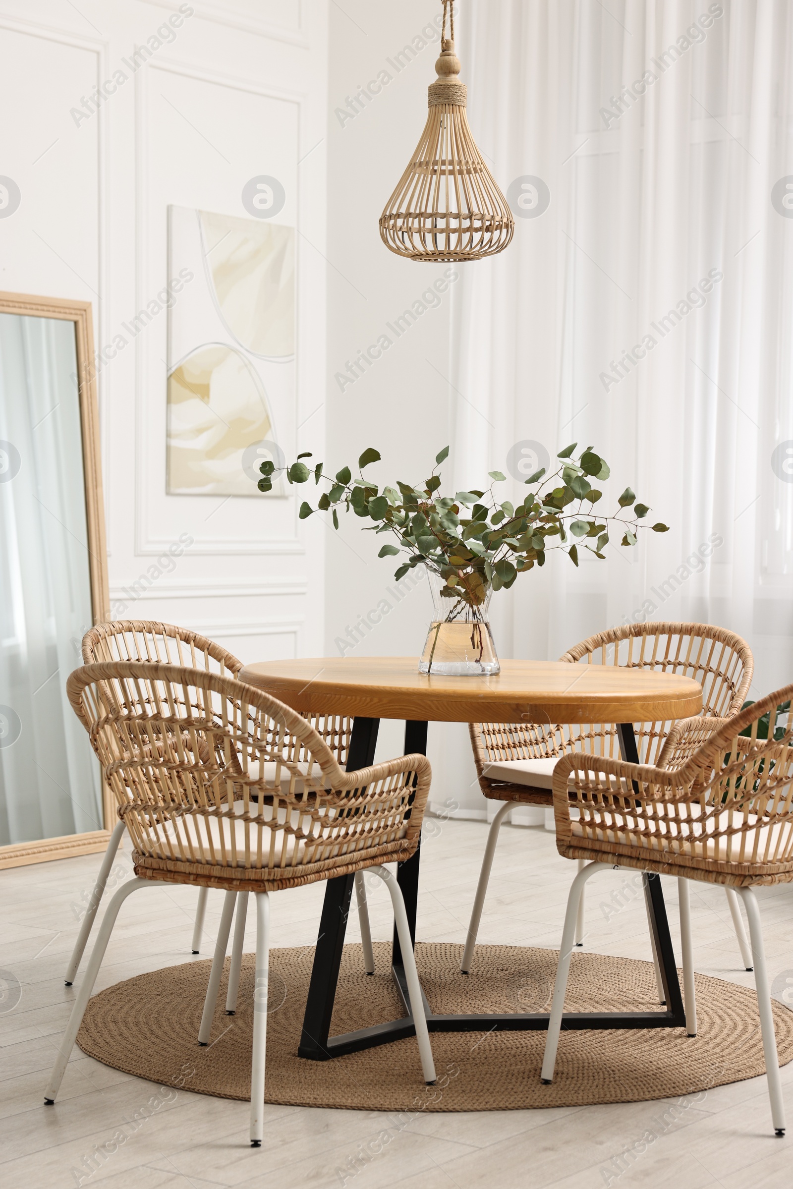 Photo of Dining room interior with comfortable furniture and eucalyptus branches