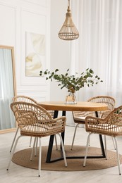 Photo of Dining room interior with comfortable furniture and eucalyptus branches