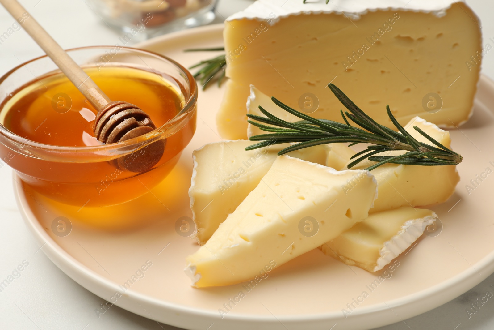 Photo of Tasty Camembert cheese with rosemary and honey on white table, closeup