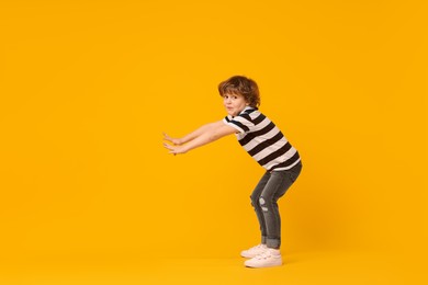 Photo of Happy little boy dancing on yellow background
