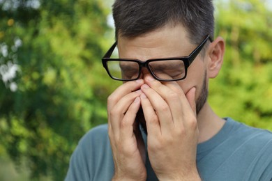Photo of Man suffering from eyestrain outdoors on sunny day, closeup