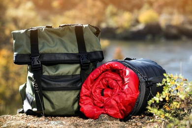 Photo of Backpack and sleeping bag on ground outdoors. Camping equipment