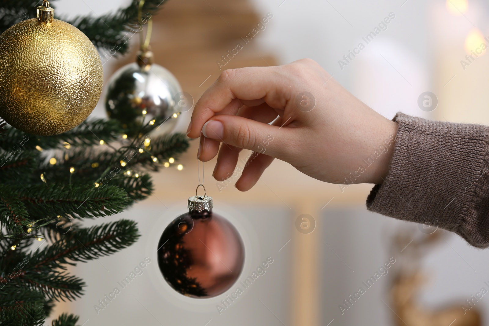 Photo of Woman holding brown ball near Christmas tree indoors, closeup