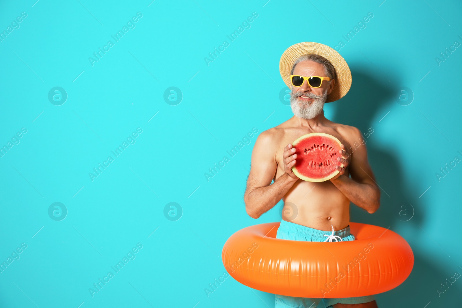 Photo of Shirtless man with inflatable ring and watermelon on color background