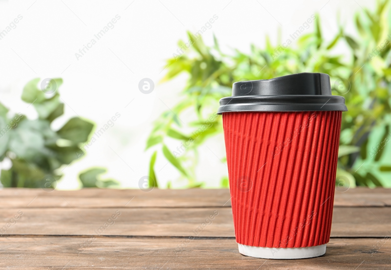 Photo of Cardboard coffee cup with lid on wooden table. Space for text
