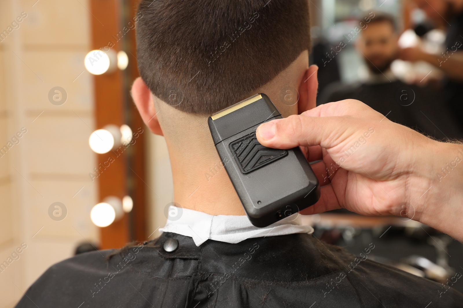 Photo of Professional hairdresser working with client in barbershop, closeup