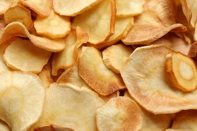 Tasty homemade parsnip chips as background, top view