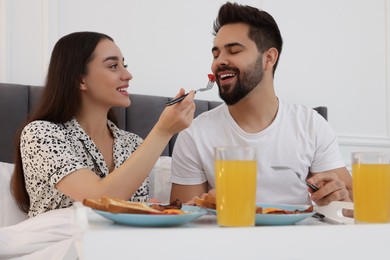 Happy couple having breakfast on bed at home