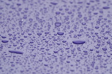 Photo of Water drops on lilac background, closeup view