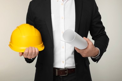 Architect with hard hat and draft on gray background, closeup