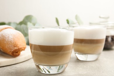 Photo of Delicious latte macchiato and croissant on light grey table