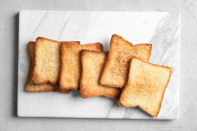 Photo of Board with toasted bread on light background, top view