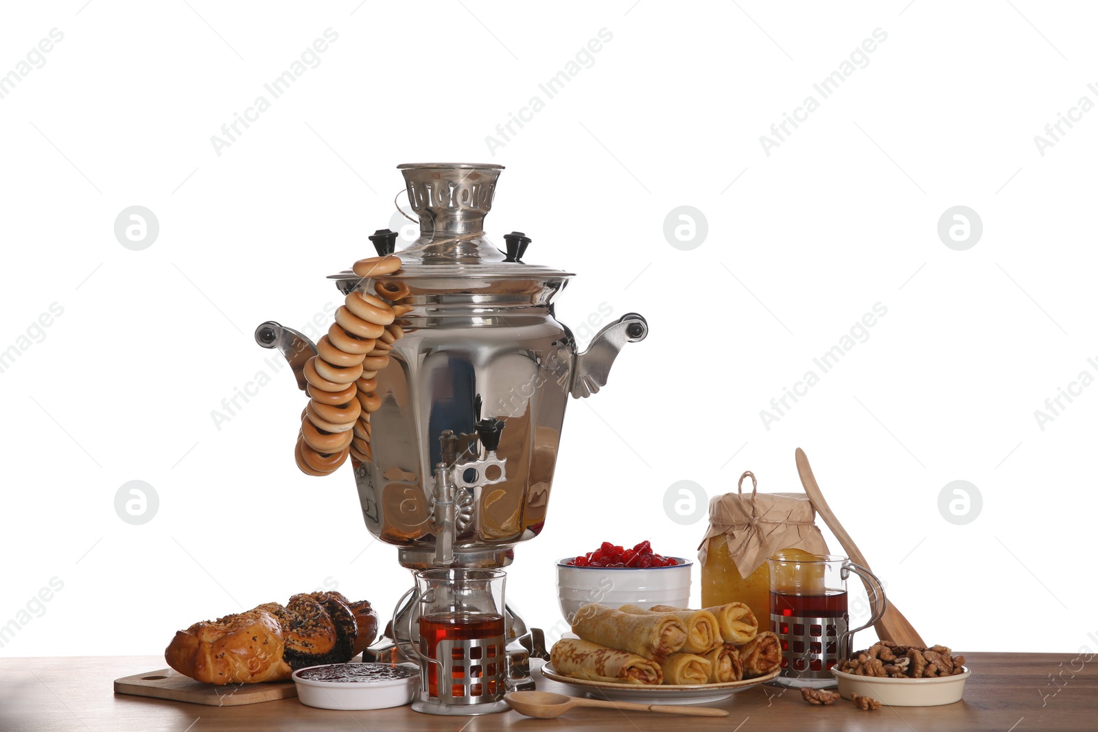 Photo of Traditional Russian samovar with treats on wooden table against white background