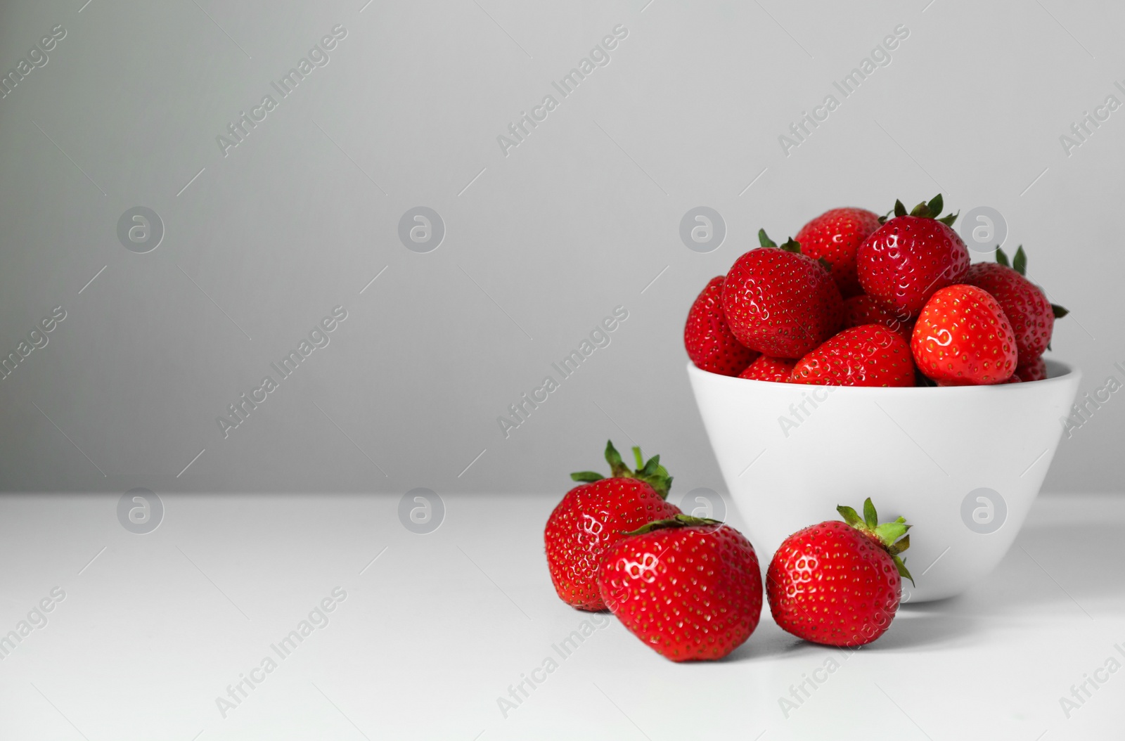 Photo of Fresh juicy strawberries on white table, space for text