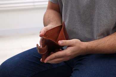 Man with empty wallet at home, closeup