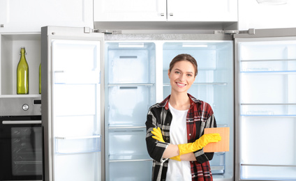 Photo of Woman with rag near clean refrigerator at home