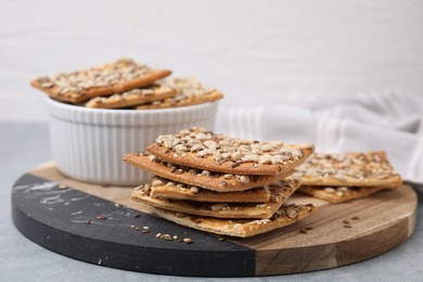 Photo of Cereal crackers with flax, sunflower and sesame seeds on grey table, closeup